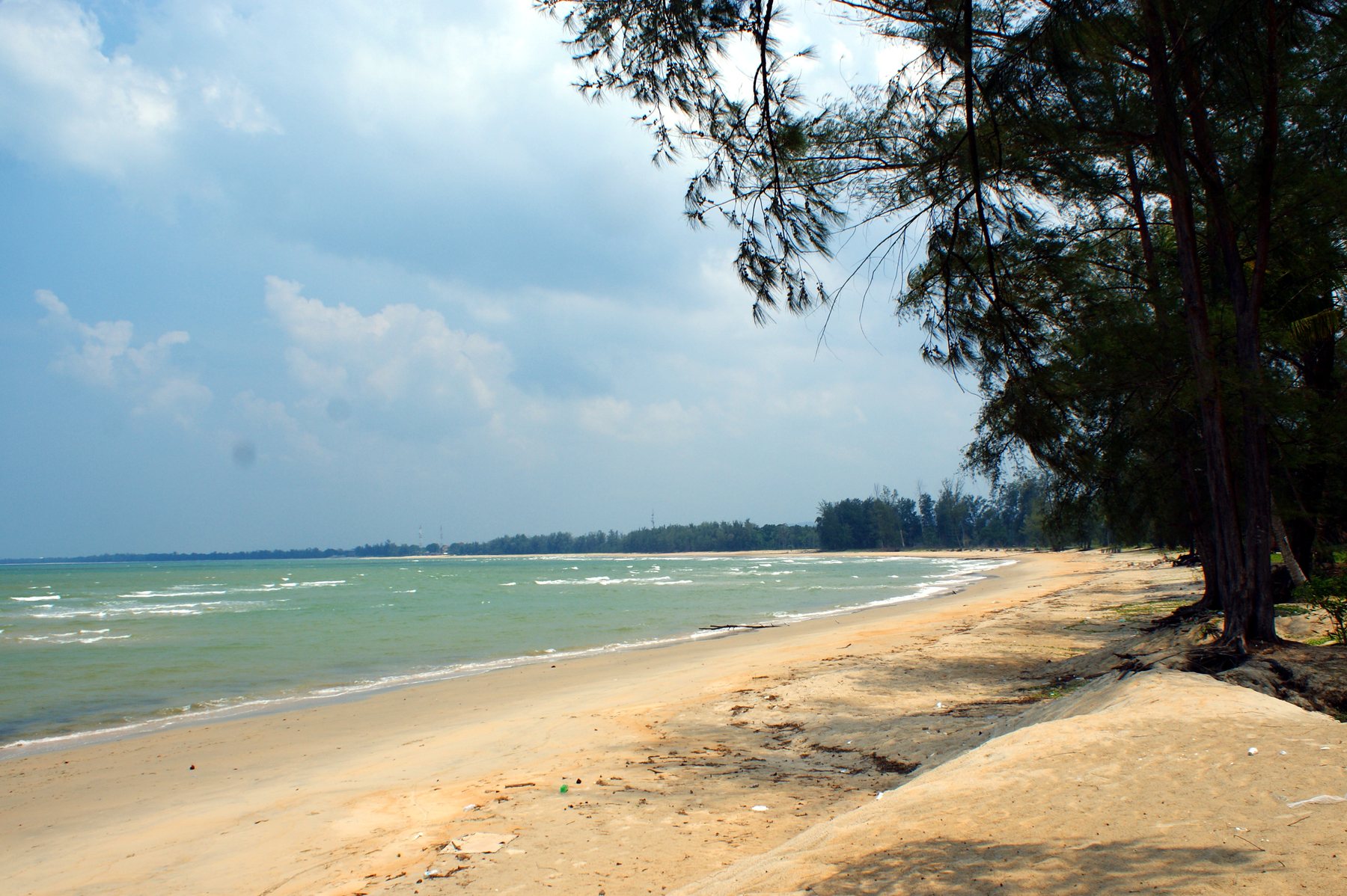 The wide sandy sweep of Pantai Cherating under a cloudy sky, figures small in the distance